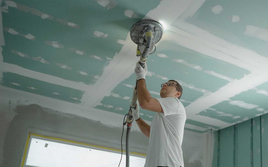 Instalador de drywall realizando el proceso de lijado