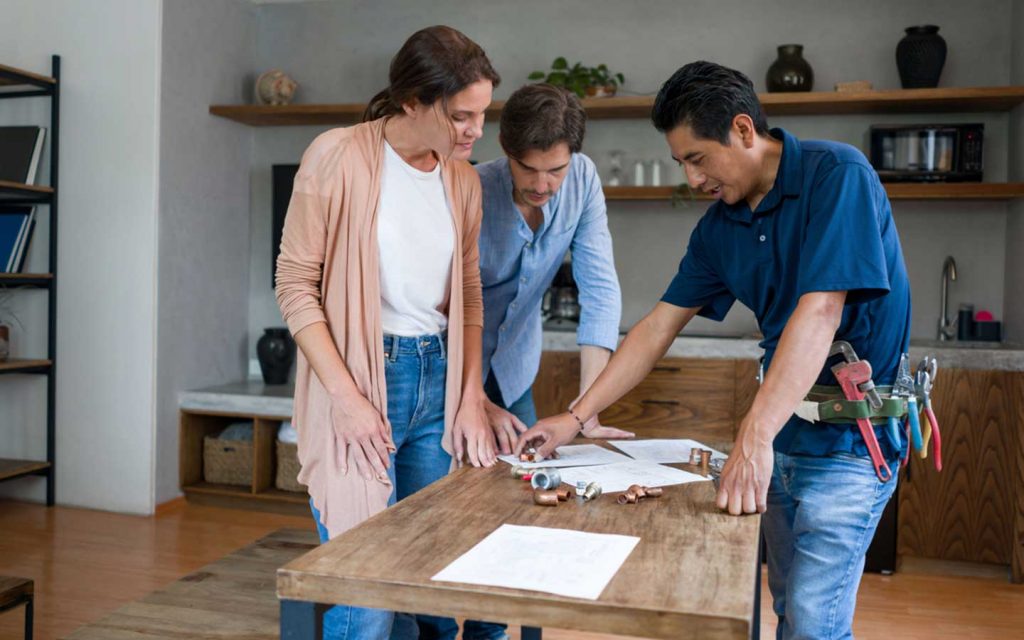 Pareja y trabajador de remodelaciones revisando elementos y documentos para trabajos en casa