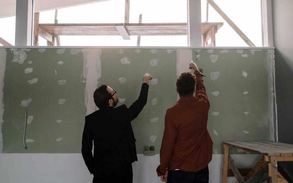 2 personas revisando calidad de un muro de drywall