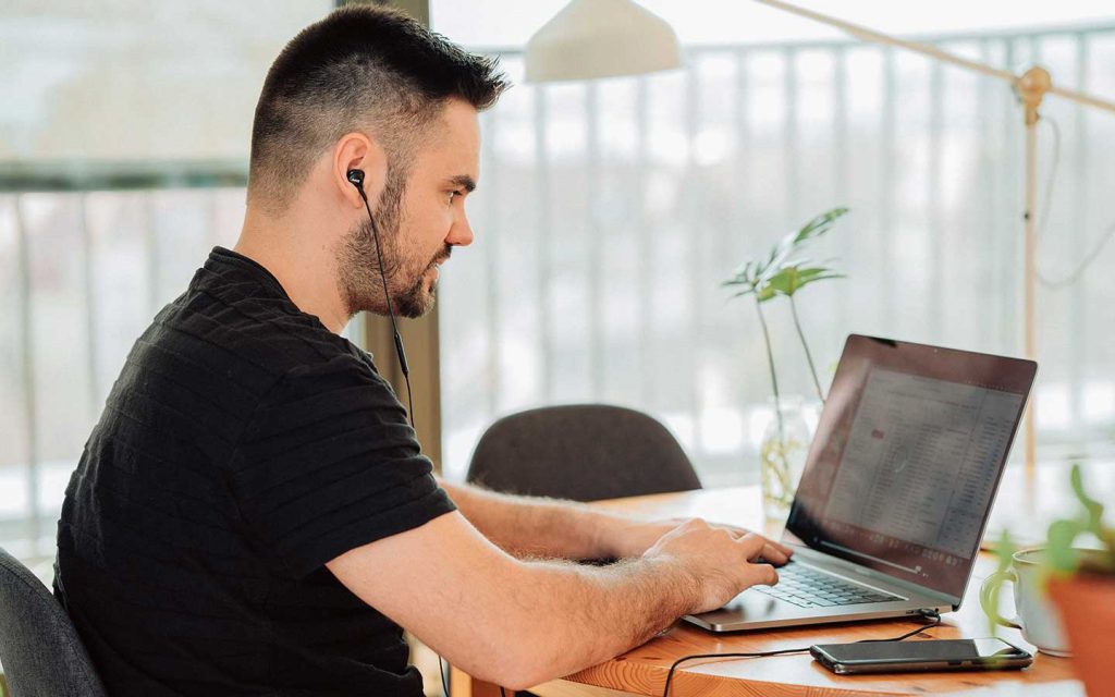 Hombre joven sentado frente a un computador portatil